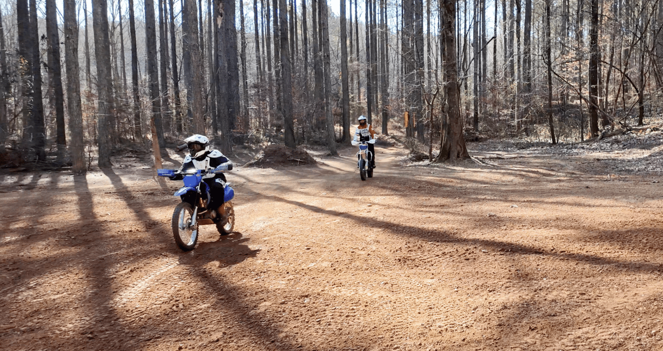Dirt bike riders on wooded trails at Off-Road Adventures at Durhamtown