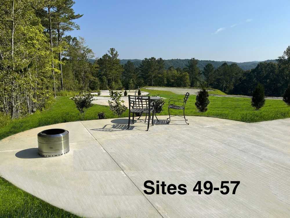 Concrete RV patio with a table, chairs, and fire pit at Talking Rock Motorcoach Resort